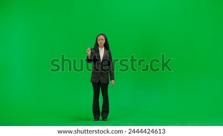 Young female reporter isolated on chroma key green screen background. Full shot african american woman tv news host uses virtual screen, swiping gesture.