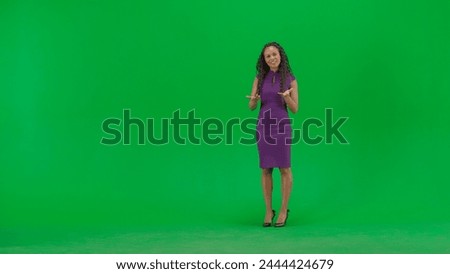 Female in dress isolated on chroma key green screen background. Full shot african american woman tv news host standing talking looking at camera.