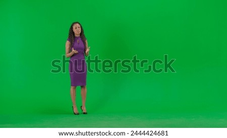 Female in dress isolated on chroma key green screen background. Full shot african american woman tv news host standing talking looking at camera. Royalty-Free Stock Photo #2444424681
