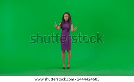 Female in dress isolated on chroma key green screen background. Full shot african american woman tv news host uses virtual screen, swiping zooming clicking.