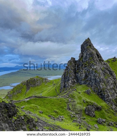 AERIAL: Majestic basalt rock towers on the way to the famous Old Man of Storr. The smallness of a hiker in comparison with huge rock sculptures above beautiful landscape on picturesque Isle of Skye.