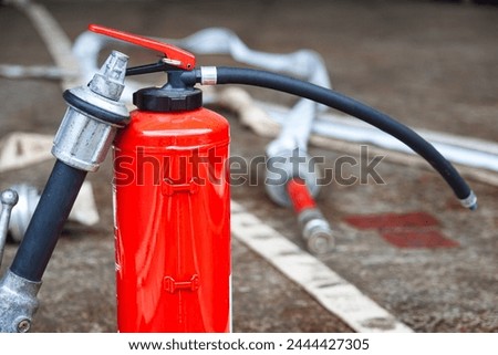 Red fire extinguisher cylinder with unwound fire hoses. Royalty-Free Stock Photo #2444427305