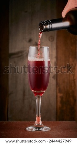Red wine being poured in to a wine glass with a wooden background.