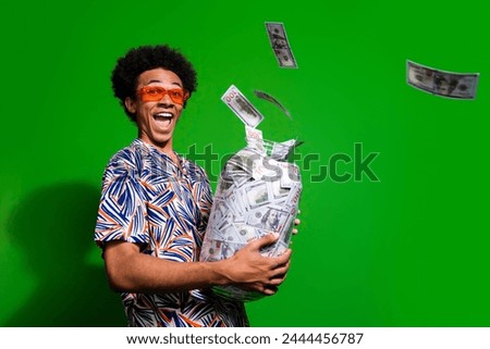 Photo of excited impressed man dressed print shirt dark glasses collecting cash glass jar empty space isolated green color background