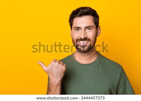 Photo of funky good mood man wear khaki t-shirt showing thumb empty space isolated yellow color background