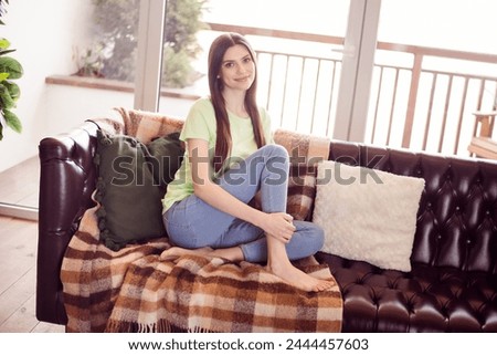 Full length body size photo young woman sitting on sofa smiling relaxing in cozy athmosphere