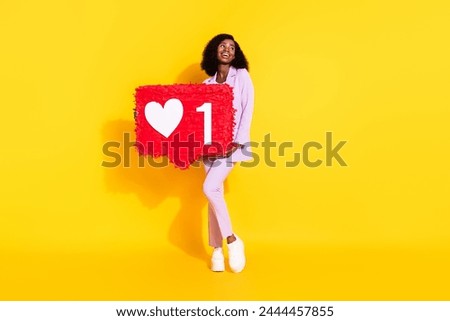 Full size photo of young happy lovely charming afro girl hold hug pinata look copyspace isolated on yellow color background