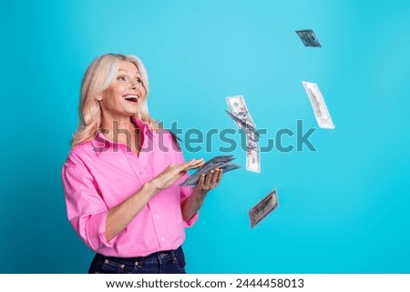 Photo of pretty pensioner female throw flying money spend excited wear trendy pink smart casual outfit isolated on cyan color background