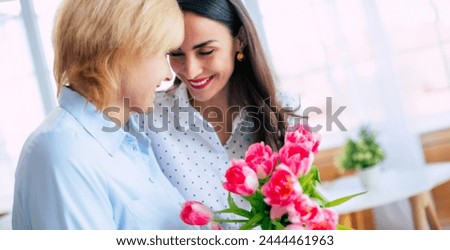 Banner image of happy daughter and mom with tulips bouquet. Birthday, Mothers day, women's day, retired, family, relation, motherhood.