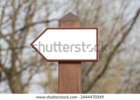Dirrection arrow. Signpost outdoor. Empty copy space sign. Tourist destination. Blank guide post. Forest road hiking trail. Trees behind. City park landscape. Sightseeing route.