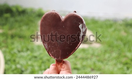 little girl's hand hold a chocolate ice cream with heart shape. valentine concepts