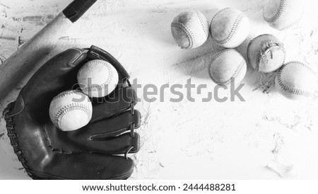 Old used baseball balls with bat and glove by copy space in black and white, sports equipment flat lay background scene.