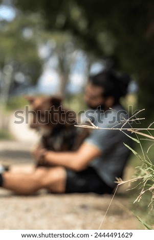 blurred photo of man sitting on road with dog for copy space
