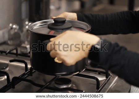 Cropped image, Hands of female chef remove pot from gas stove after cooking already  in kitchen