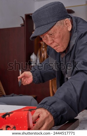 An old calligrapher is carefully writing the Chinese Spring Festival couplets Royalty-Free Stock Photo #2444517771