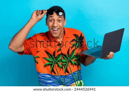 Photo of cheerful impressed guy dressed print shirt working modern device isolated blue color background