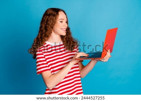 Photo of intelligent smart woman with wavy hairdo dressed striped t-shirt look at laptop read email isolated on blue color background