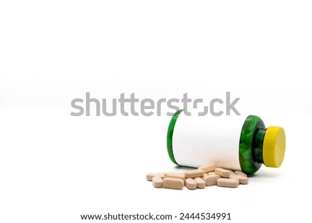 Medicine bottle lying down with blank label ready for editing or writing on it, next to pills, isolated on white background, with copy space. Concept of time, medicine, pharmaceuticals, business