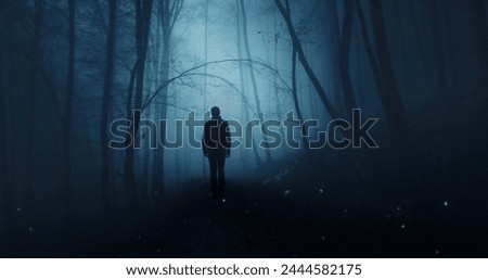  Man silhouette in mystic dark blue foggy forest.