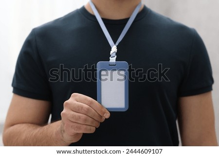 Man with blank badge indoors, closeup view