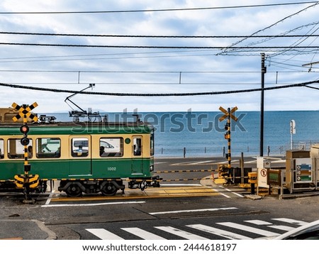 enoden train running at the seaside railroad crossing at kamakura kokomae station in kamakura city, kanagawa prefecture,  Royalty-Free Stock Photo #2444618197