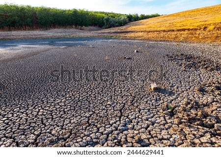 Barren terrain with cracks on dry land, Dry lake during drought Royalty-Free Stock Photo #2444629441
