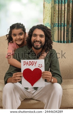 Father holding greeting card of daddy made by her daughter on Father's day