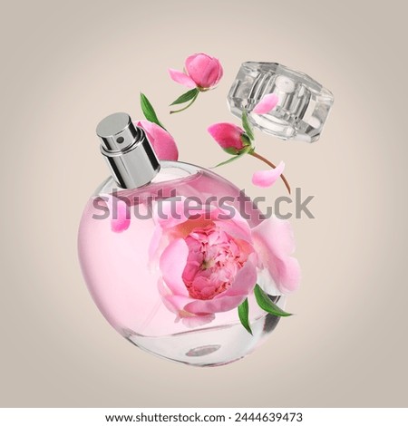 Bottle of perfume and peonies in air on dark beige background. Flower fragrance
