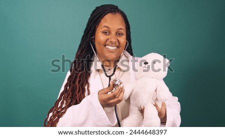 Young Black female doctor demonstrating monitoring heartbeat with a teddy bear Royalty-Free Stock Photo #2444648397