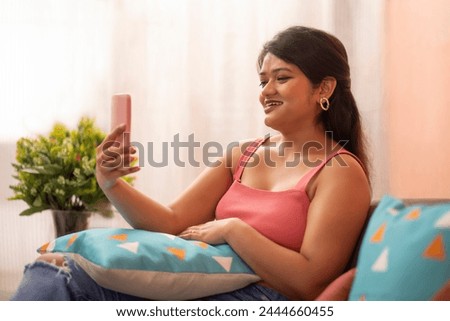 Young woman having video call while sitting on sofa in living room