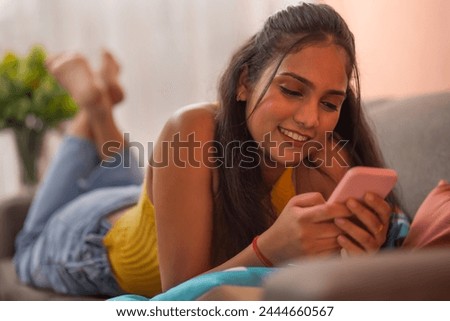 Young woman using mobile phone while relaxing on sofa in living room