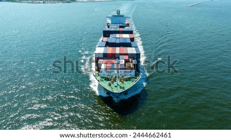 Aerial front view of cargo ship with contrail in the ocean sea ship carrying container and running from container international port smart freight shipping by ship service	

