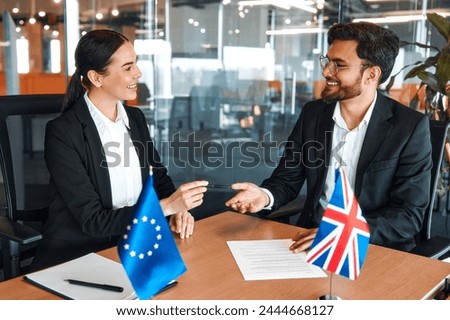 The flags of Great Britain and the European Union are on the table during negotiations between diplomats and businessmen. Representatives discuss relations between countries, signing a treaty.