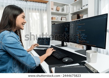 Young Asian in IT developer creating with typing online information on pc with coding program data of website application, wearing jeans shirt. surrounded by safety analysis two screens. Stratagem.