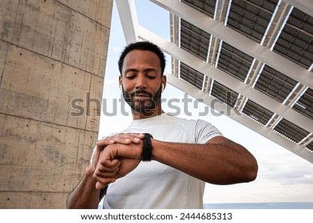 African American man checking pulse in smart watch. Black male athlete with wireless earphones using smart watch to put on music. Sport and technology concept. Royalty-Free Stock Photo #2444685313