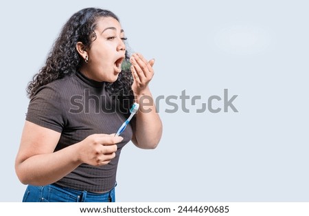Young woman holding brush with bad breath isolated. Person with brush and bad breath isolated, Person with halitosis Royalty-Free Stock Photo #2444690685