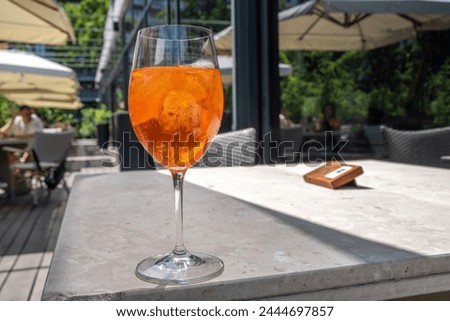 Girl drink iced alcohol Aperol spritz cocktail on summer terrace, in cafe or restaurant