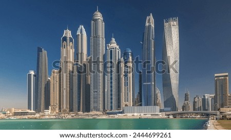 Scenic view of Dubai Marina tallest Skyscrapers with boats timelapse, Skyline, View from sea, United Arab Emirates. Blue sky at sunny day Royalty-Free Stock Photo #2444699261