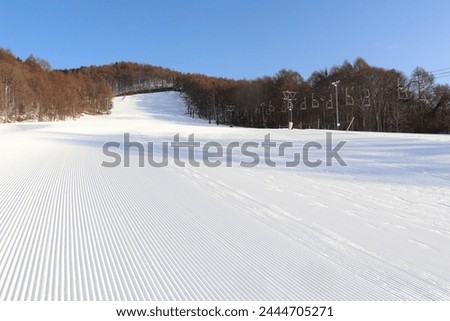 Striped pattern of pisten on the ski slope in the morning with compacted snow web background
