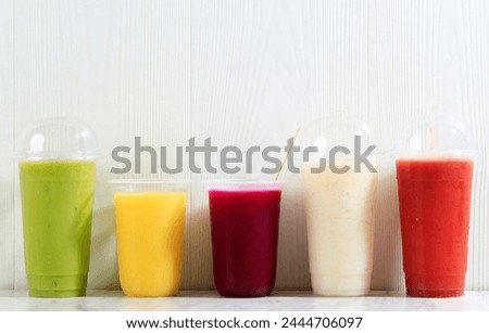 Different Color Juice on Plastic Cup Packaging, on White Table Background 