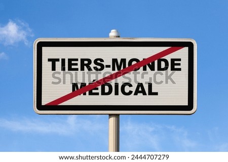 A French exit city sign against a blue sky with written in the middle in French "Tiers-monde médical", meaning in English "Medical third world".