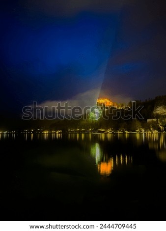 Bled castle in Slovenia. Night view of the lake with lights reflecting in the water.
