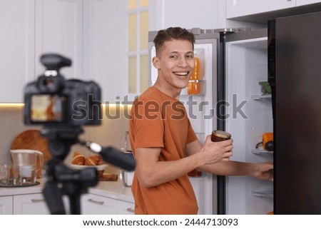Smiling food blogger explaining something while recording video in kitchen Royalty-Free Stock Photo #2444713093