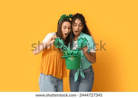 Beautiful young women with leprechaun hat and decorative glasses on yellow background. St. Patrick's Day celebration