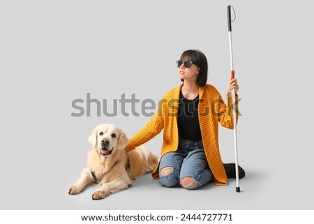 Blind woman with guide dog on grey background Royalty-Free Stock Photo #2444727771