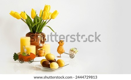 Easter eggs, yellow tulips, candles and souvenirs on a white table. Photo