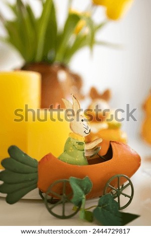 Easter souvenir, bunny on a carrot and yellow candles. Postcard. Photo