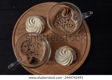 Coffee with cream, chocolate, cinnamon sticks, and mango marshmallows, poured into heart-shaped class cups and carefully set for two on a wooden tray Royalty-Free Stock Photo #2444742491
