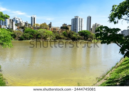 Residential buildings on the edge of a lake with many trees. Blue sky with clouds. City of Belo Horizonte. Brazil.