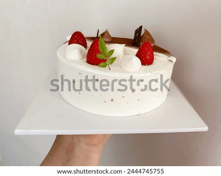 A decorated half and half birthday cake of a sponge cake with whipped cream and chocolate paste topped with chocolate pieces and fresh strawberry fruit, birthday, holidays and anniversary concept.